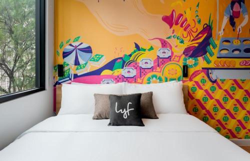 a bedroom with two white beds with a colorful wall at lyf Chinatown Kuala Lumpur in Kuala Lumpur