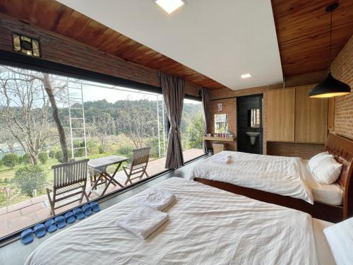 two beds in a room with a large window at Scent Bungalow Hotel in Da Lat