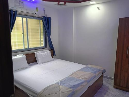 a small bed in a room with a window at Soumil 102 in Chinchwad