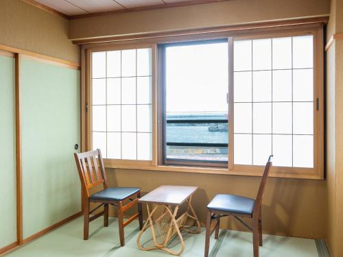 a room with two chairs and a table and two windows at Sumiyoshiya in Nagaoka