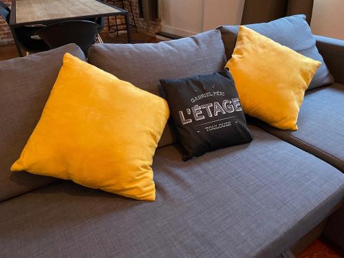 a book sitting on a couch with yellow pillows at L'Étage, hypercentre Toulousain, Climatisé in Toulouse