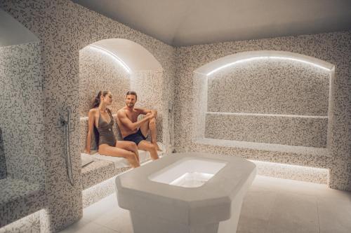 un hombre y una mujer sentados en un baño en The Green Park Hotel, en Cavallino-Treporti