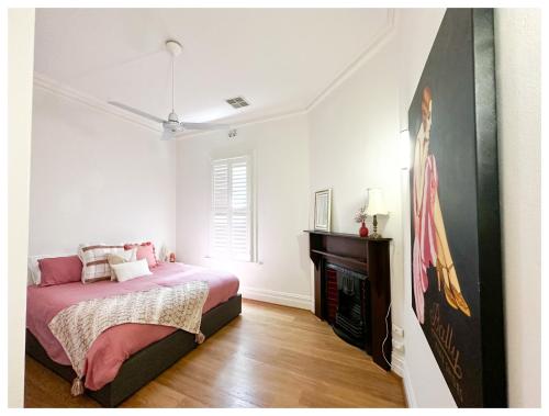 a bedroom with a pink bed and a fireplace at HAVEN: Stunning Unley *history*location*charm 3bd in Unley