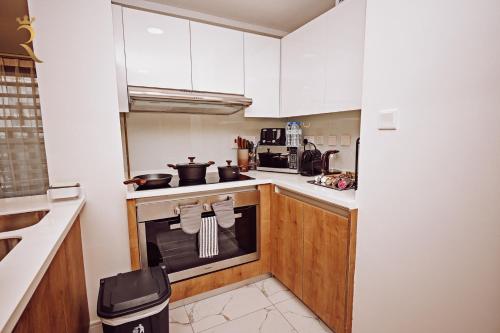 a kitchen with white cabinets and a stove top oven at 3BR Al Raha Haven - Chic Coastal Escape in Abu Dhabi