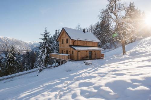 a wooden cabin in the snow with the sun behind it at Chalet Jochwand Bad Goisern in Bad Goisern