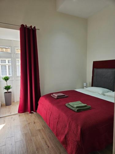 ein Schlafzimmer mit einem roten Bett mit einem roten Vorhang in der Unterkunft SUNNY APARTMENT 44 MALTA in Taʼ Xbiex