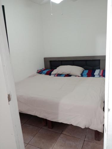 1 dormitorio con 1 cama con sábanas y almohadas blancas en Apartamento Puente del Zorro, en Ciudad Juárez