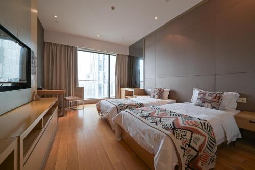 a hotel room with two beds and a flat screen tv at Snug Gaokong Jiangjing Hotel in Guangzhou
