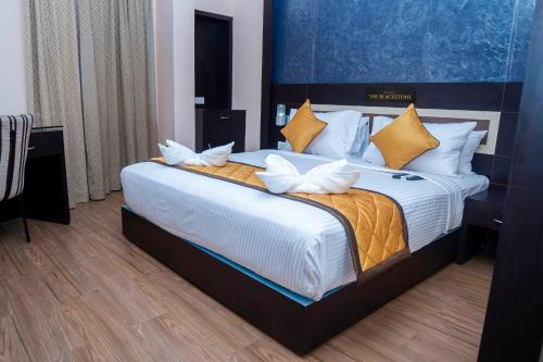a bedroom with a large bed with white and yellow pillows at Hotel The Black Stone in Bengaluru