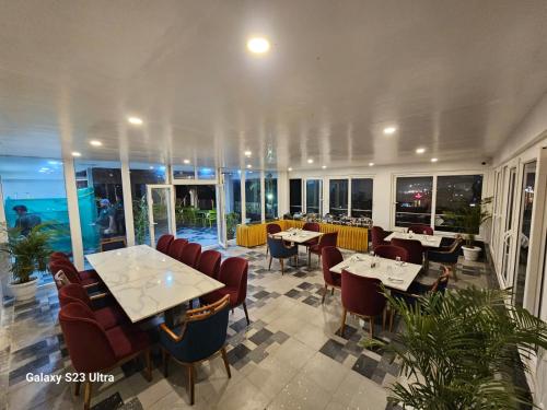 a restaurant with tables and chairs and windows at Pipul Ocean View Resort in Puri