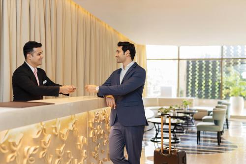 two men in suits shaking hands at a counter at Radisson Blu Hotel New Delhi Dwarka in New Delhi