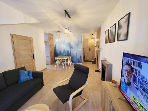 uma sala de estar com um sofá, uma televisão e uma mesa em Apartament Spokojna Wisła em Wisla