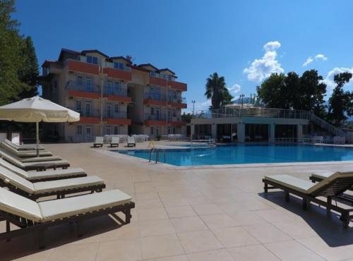 a large swimming pool with lounge chairs and a hotel at Grand Cnr Hotels in Fethiye