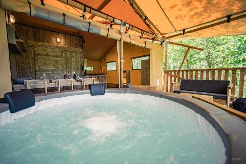 Un bain à remous est installé au milieu d'une terrasse. dans l'établissement Tente lodge insolite Jacuzzi privatif en pleine nature, à Thiel-sur-Acolin