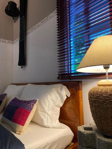 a bedroom with a bed with a lamp and a window at Chang's Hideaway homestay ConDao in Con Dao