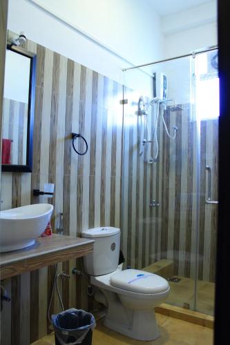 a bathroom with a toilet and a sink and a shower at Raj Mahal Inn in Wadduwa