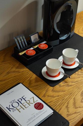a desk with two coffee cups and a coffee maker at HVD Grand Hotel Suhl Business & Leisure in Suhl