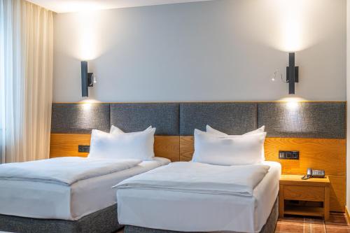two beds in a hotel room with white pillows at HVD Grand Hotel Suhl Business & Leisure in Suhl
