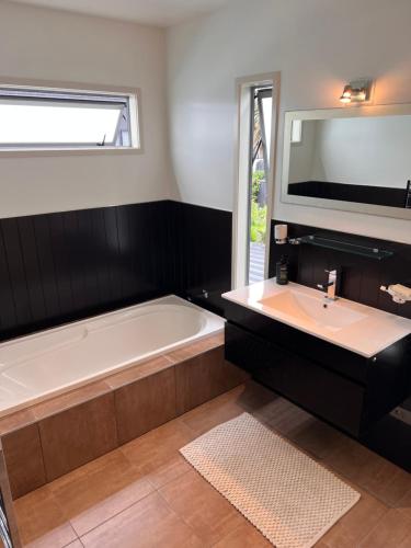 a bathroom with a tub and a sink at Modern Home Central Mount in Mount Maunganui