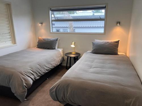 two beds in a room with a window at Modern Home Central Mount in Mount Maunganui