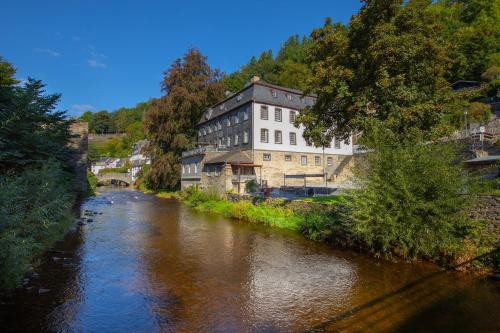 a building sitting next to a river next to a building at Elbershof Monschau in Monschau