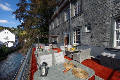 an outdoor patio with tables and chairs and a river at Elbershof Monschau in Monschau