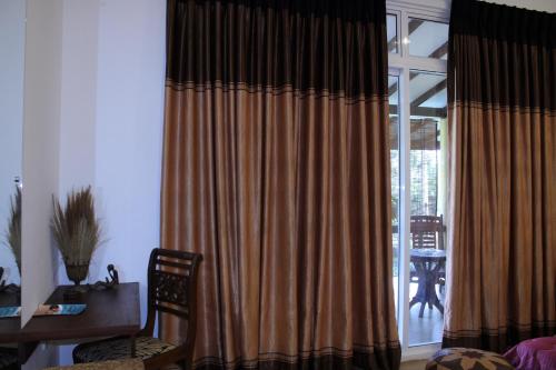 a room with a desk and a window with curtains at Raj Mahal Inn in Wadduwa