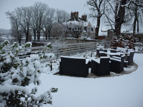 a garden covered in snow with a house in the background at Le Prieuré Saint Agnan in Cosne-Cours-sur-Loire
