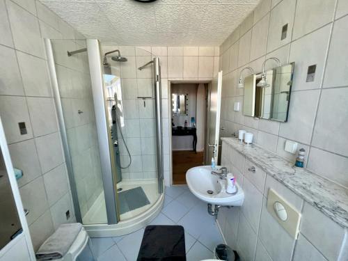 ein weißes Bad mit einer Dusche und einem Waschbecken in der Unterkunft Ferienwohnung Ankommen & Wohlfühlen in Cuxhaven