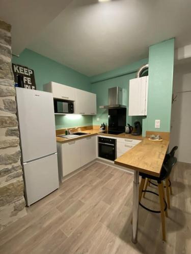 une cuisine avec une table et un réfrigérateur blanc dans l'établissement Charmant studio idéalement placé et paisible !, à Oloron-Sainte-Marie