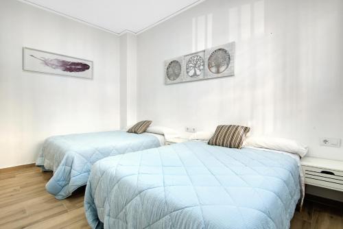 Duas camas num quarto com paredes brancas em Gandia Confort Lope de Vega em Gandia