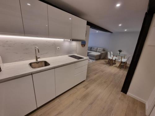 a kitchen with white cabinets and a living room at Apartamento centro Santander in Santander