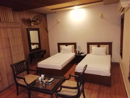 a hotel room with two beds and a table at silk.hotel in Faisalabad