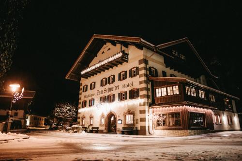 un gran edificio en la nieve por la noche en Hotel - Wirts'haus "Zum Schweizer", en Lofer