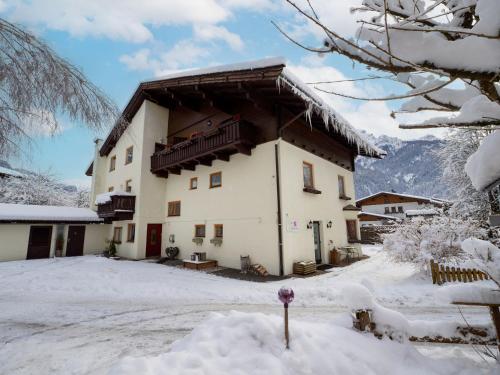 ein großes Gebäude mit Balkon im Schnee in der Unterkunft Haus Alpenrose in Waidring