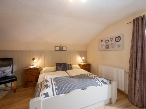 a bedroom with a large bed and a chair at Haus Alpenrose in Waidring