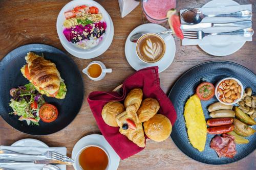 a wooden table with plates of food and cups of coffee at Fairfield by Marriott Bali South Kuta in Kuta