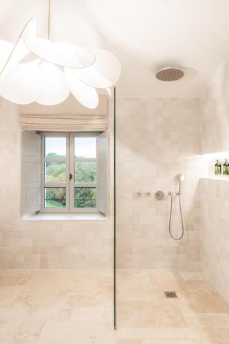 a bathroom with a shower with a window and a chandelier at Le Couvent des Minimes, un Hôtel & Spa L'Occitane en Provence in Mane