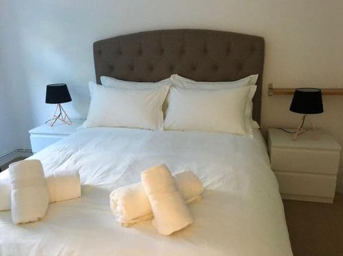 un grande letto bianco con due cuscini sopra di Victoria Park 1 bedroom flat a Londra