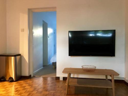 a living room with a table and a television on a wall at Victoria Park 1 bedroom flat in London