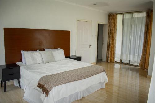 a bedroom with a large bed with a wooden headboard at Divine Heights Apartments Lilongwe Area 43 in Lilongwe