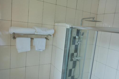 y baño con ducha y toallas blancas. en Divine Heights Apartments Lilongwe Area 43 en Lilongüe