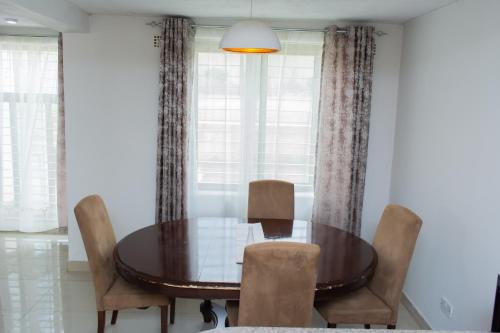 a dining room with a wooden table and chairs at Divine Heights Apartments Lilongwe Area 43 in Lilongwe