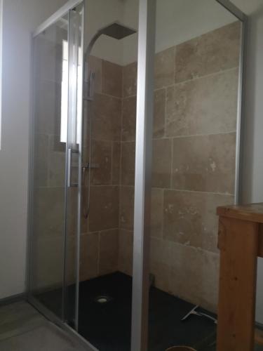 une douche avec une porte vitrée dans une salle de bain dans l'établissement gite, à Illats
