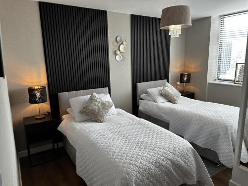 um quarto com 2 camas e lençóis brancos em Stunning two bed city Center apartment em Liverpool
