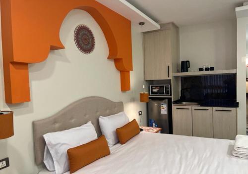 um quarto com uma grande cama branca com detalhes em laranja em Amman Trail Hotel & Studios em Amã