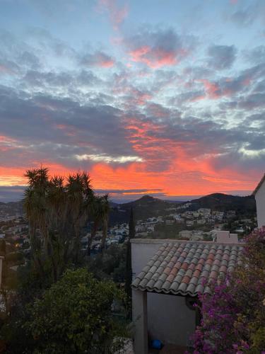 un coucher de soleil sur une ville avec un bâtiment et des palmiers dans l'établissement Appartement avec vue sur château et piscine privée, à Hyères