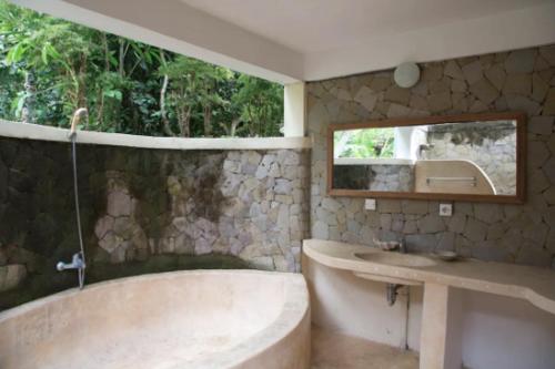 un bagno con vasca, lavandino e specchio di Abalone Sport Resort a Manggis