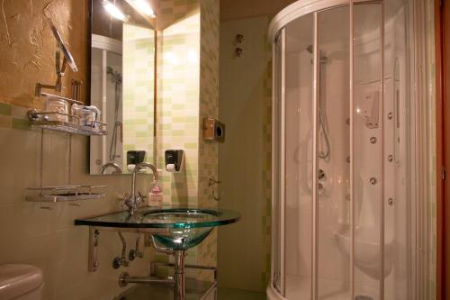 y baño con lavabo de cristal y ducha. en Casa Rural Portal de Numancia ll, en Garray