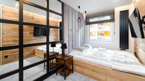 a bedroom with a bed and a wooden wall at Apartamenty Sun & Snow Panorama Karkonoszy in Karpacz